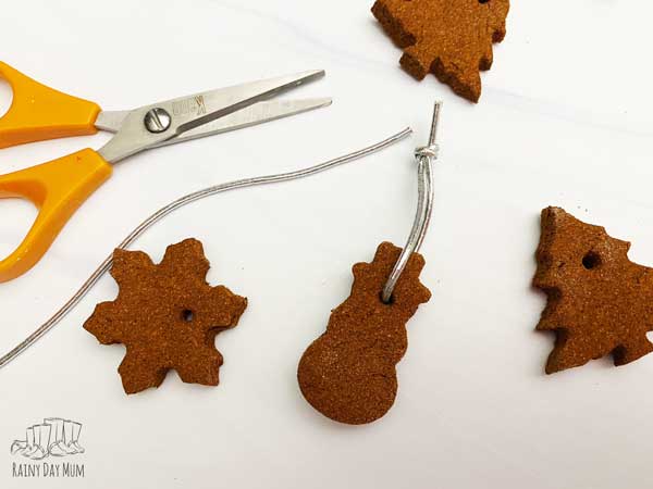 adding ribbon to the christmas tree ornaments made from applesauce and cinnamon