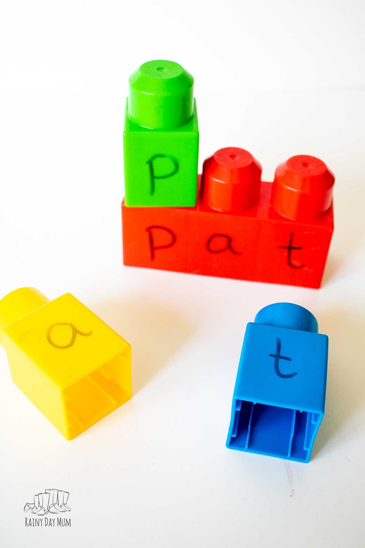 Building a word using mega blocks, the word on the 3 block is pat and single blocks are scattered around with the letters p a and t on to make the word.
