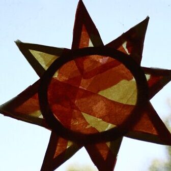 Square image of a summer sun catcher made by a preschooler for the summer solstice on a window.