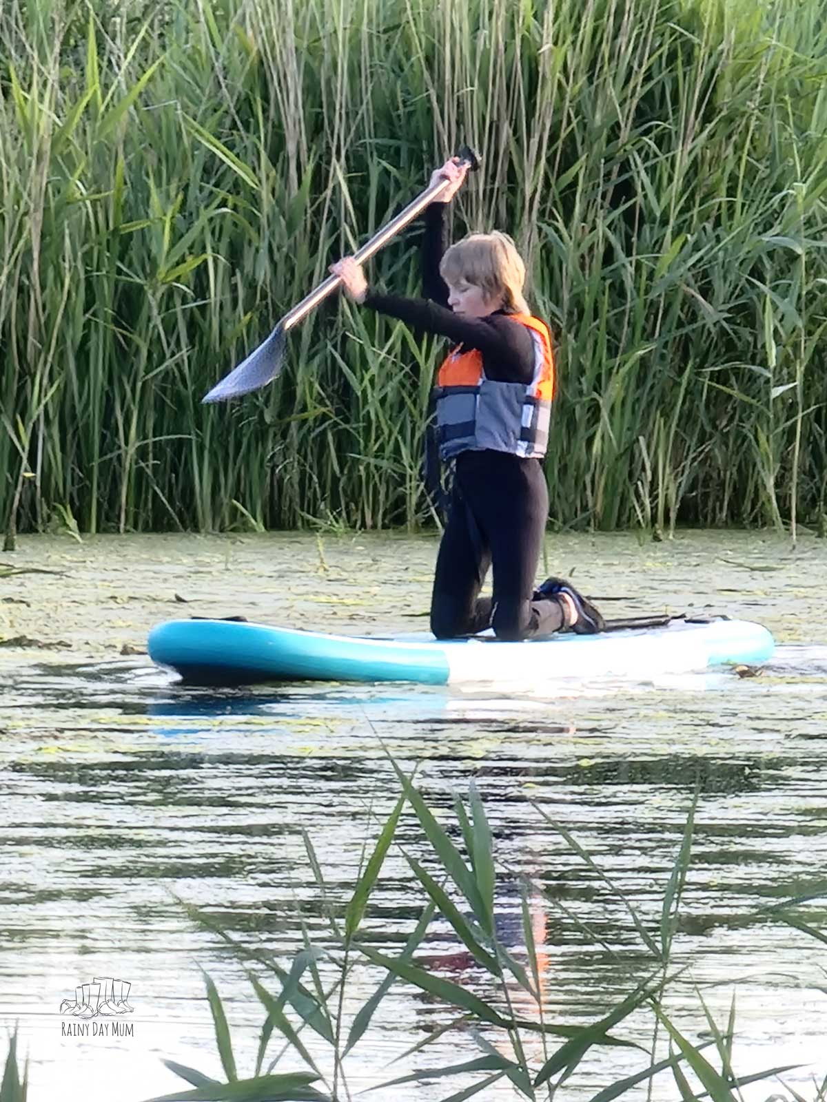Tween paddling on a river with the reeds and rushes in the background.